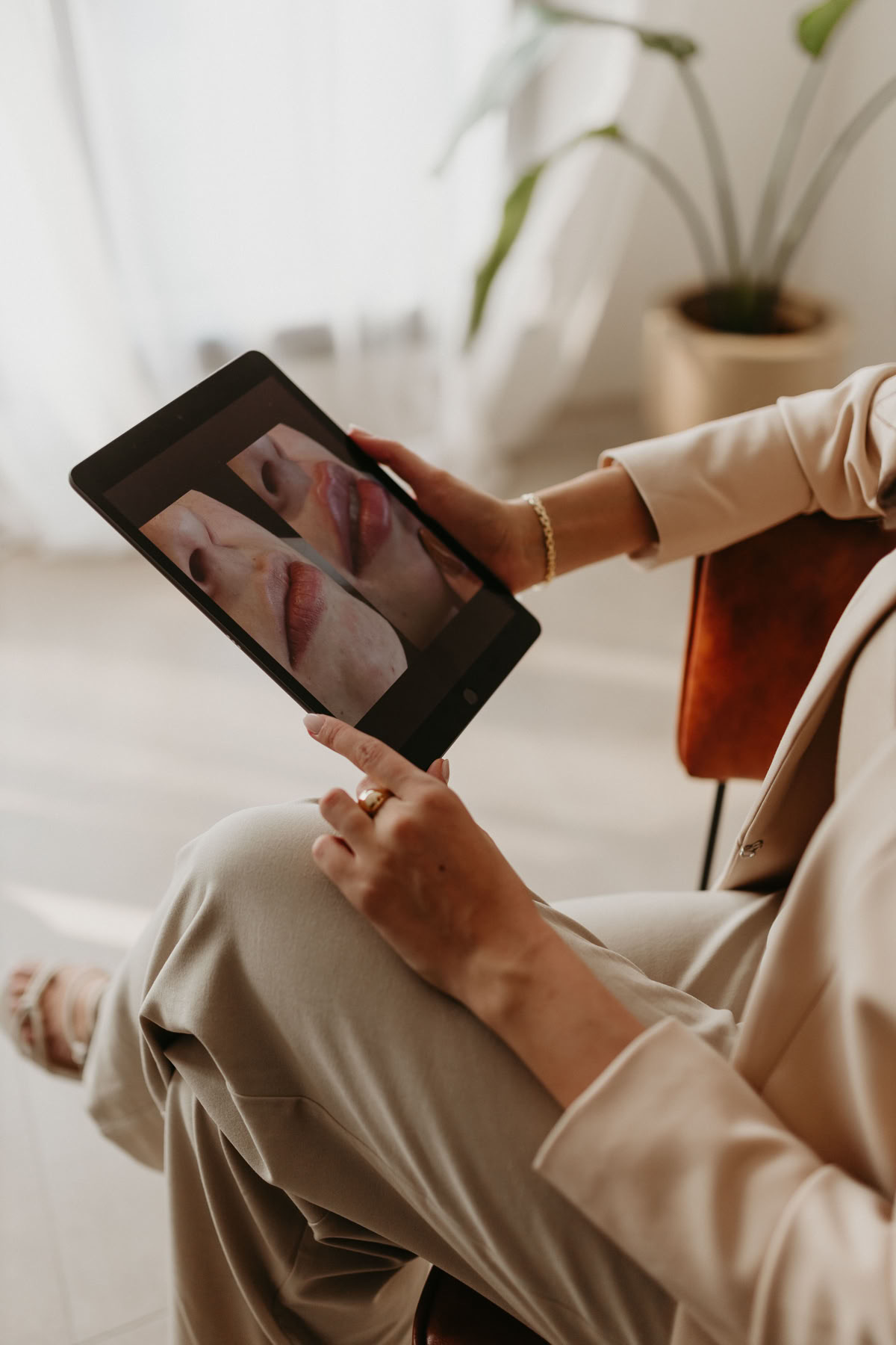 Practitioner holding a tablet showing before-and-after photographs during a consultation